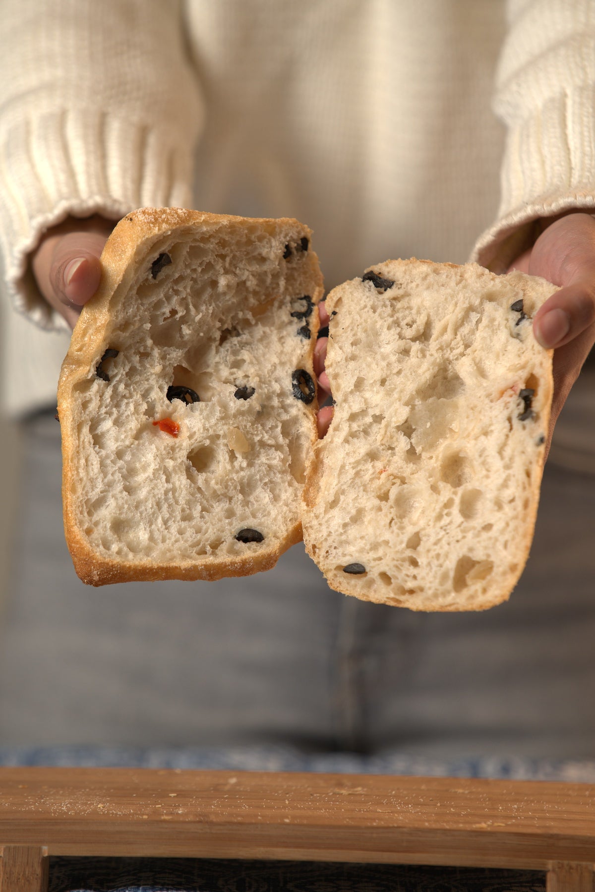 Manos abriendo una ciabatta de masa madre con aceituna y morrón, panadería Masapan en Temuco